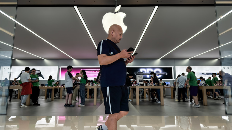 An iPhone user in front of an Apple retail store.