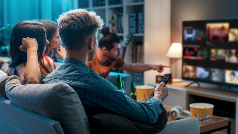 a group of young people in a living room finding a show to watch on TV