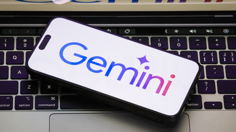 Close up of Google Gemini AI logo on a smartphone screen resting atop a keyboard.