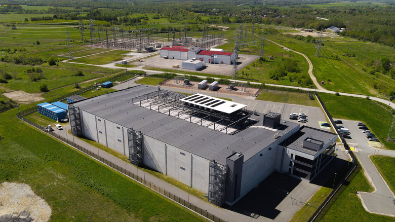 Aerial view of a data center encircled by green grass and trees at the outer perimeter.