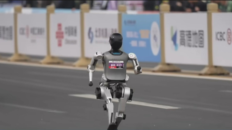 A small silver robot with a black head marches along in the half marathon race.