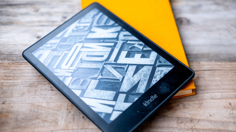 Kindle reader with black and white imagery on screen on top of a book.