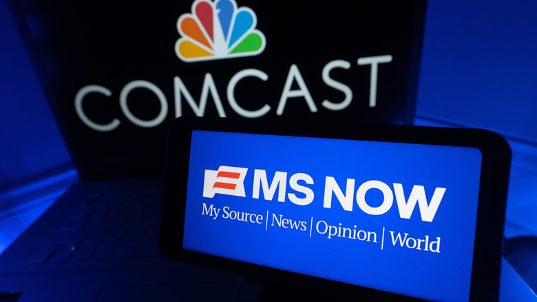 The MS NOW logo on a smartphone. The COMCAST logo on a laptop screen behind it.