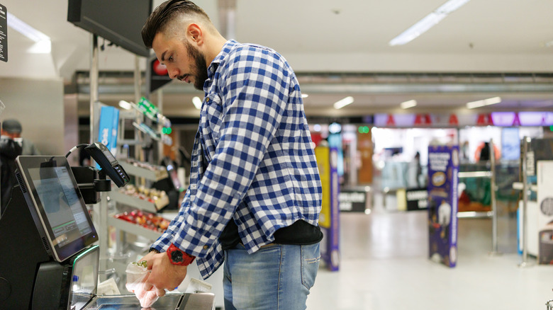 A man uses a self-checkout counter at a store