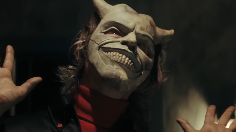 The Grabber with his mask on holding up his hands in The Black Phone