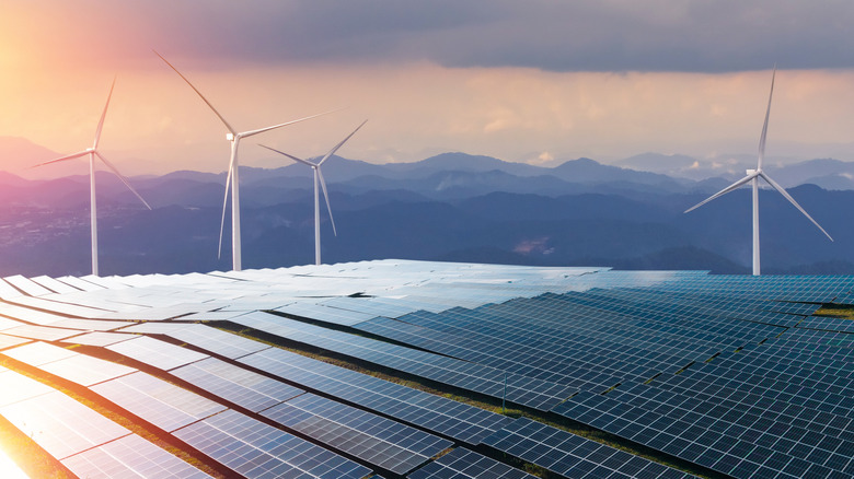 A solar and wind farm in front of mountains