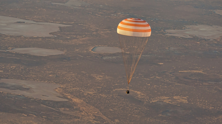 Large parachute with equipment attached and suspended underneath.