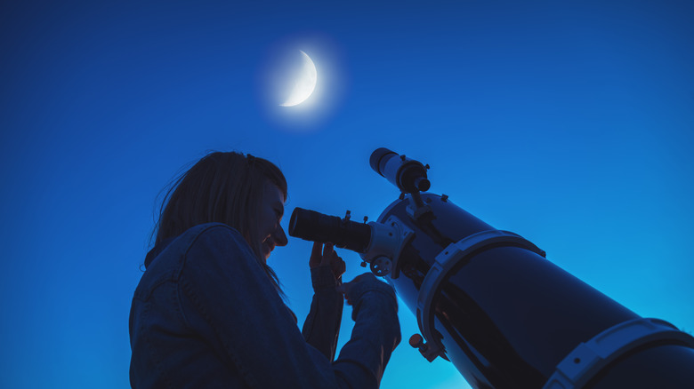 person using large telescope at night