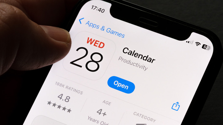 Apple calendar app on app store showing on iphone screen, thumb hovering over it
