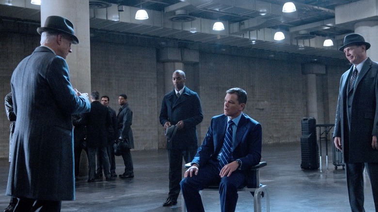 Thompson (Terence Stamp) talking to David Norris (Matt Damon) while (Harry Mitchell) stands behind him surrounded by Adjustment Burea men in The Adjustment Bureau