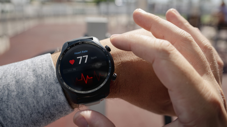 A wrist showing a smartwatch with heart rate data on screen.