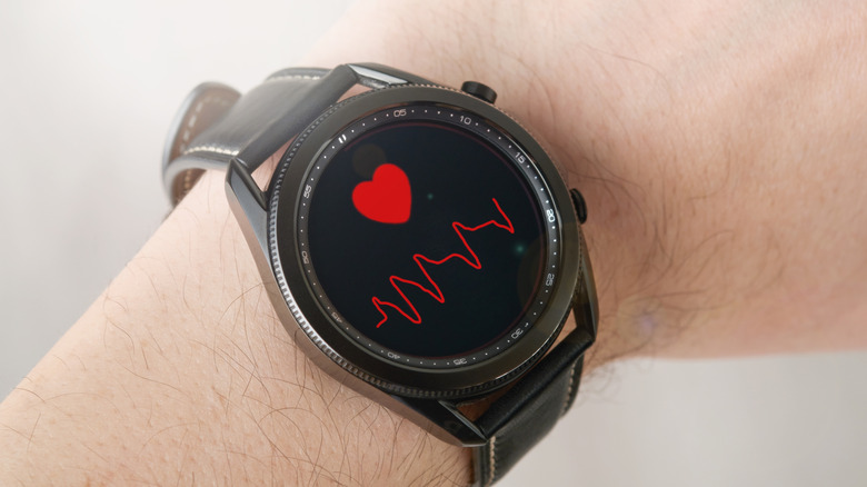 A wrist with a Samsung Galaxy Watch showing a heart rate reading.