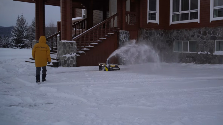 the snowblower clearing snow outside of a house