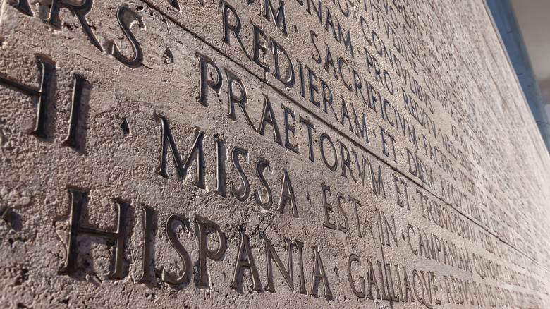 Ancient Roman inscription in Latin (The Deeds of the Divine Augustus , historical document of Roman Empire) carved into stone. Rome, Italy.
