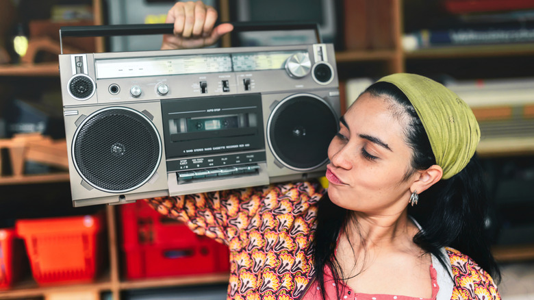 A woman carrying a retro boombox.