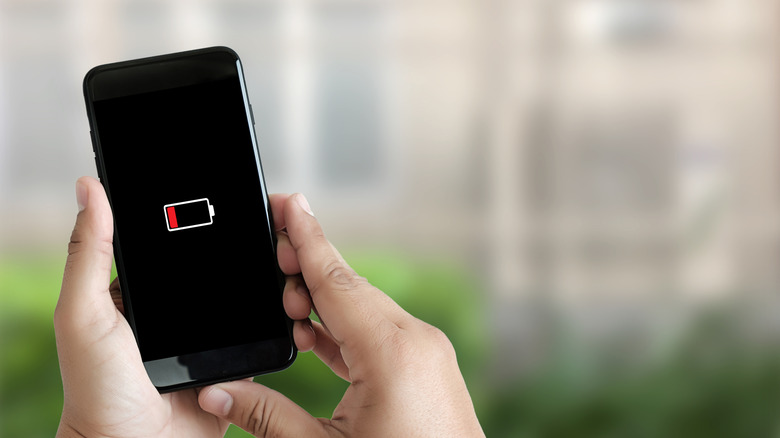 Close up of a person's hands using a smartphone with battery low warning screen