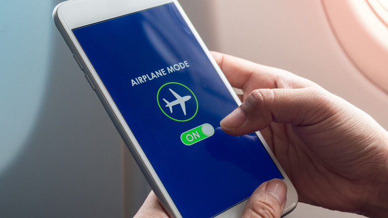 a person inside an airplane turning airplane mode on on their phone