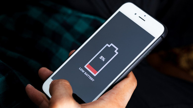 a hand holding a phone that has low battery
