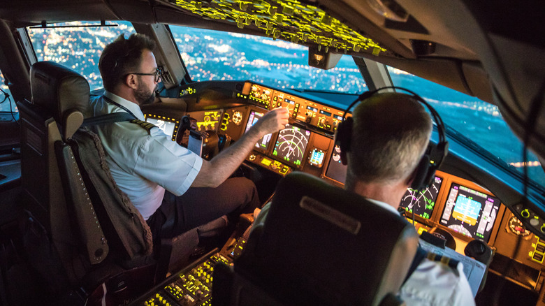 Two pilots managing software in an airplane cockpit