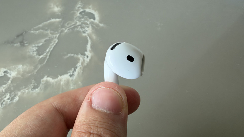 Close-up of holding one AirPods 5 earbud by the stem