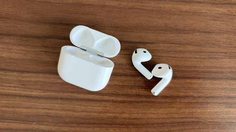 AirPods 5 buds and case sat on wood table
