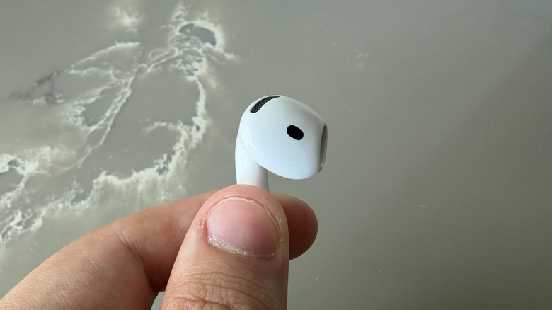 Close-up of holding one AirPods 5 earbud by the stem