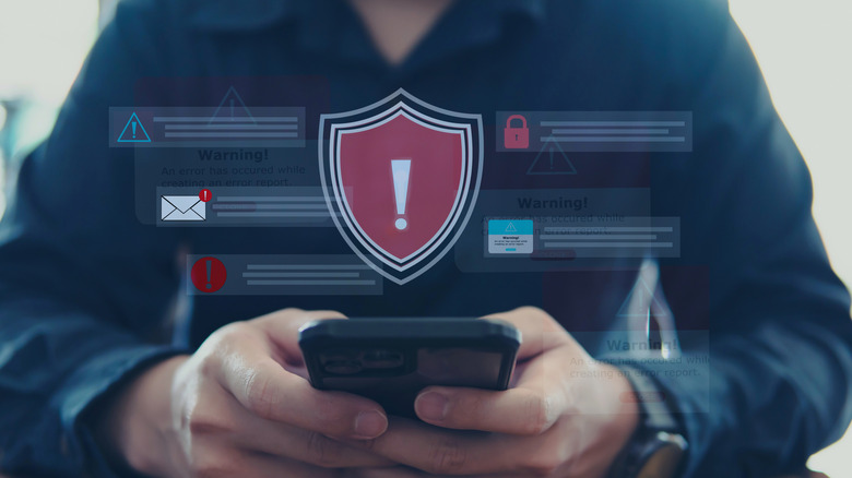 Man holding smartphone with warning symbol above it.