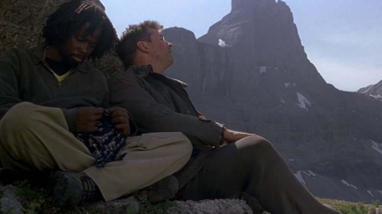 Stephen (Harold Perrineau) and Bob (Alec Baldwin) sitting on a rock exhausted in The Edge