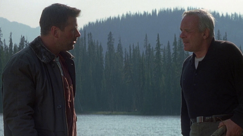 Bob (Alec Baldwin) and Charles (Anthony Hopkins) looking at each other baffled at the lake in The Edge