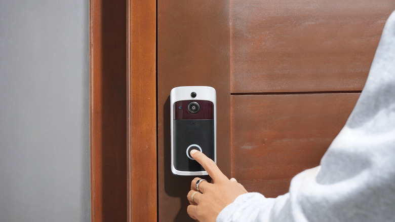 Person pressing a button on a doorbell camera.