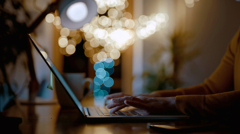 Person working on computer late at night illuminated by soft warm lights