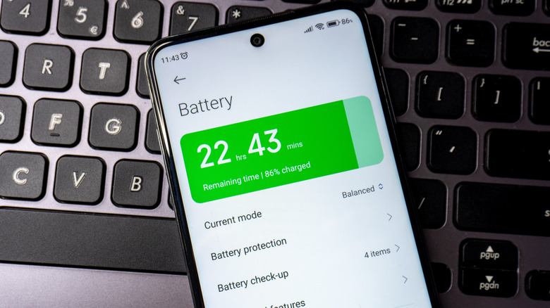 An Android phone showing battery settings resting on a keyboard