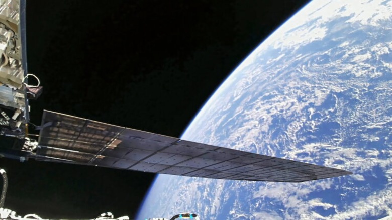 The wing of an Amazon LEO satellite as it orbits directly over Earth, our planet can be seen in the background