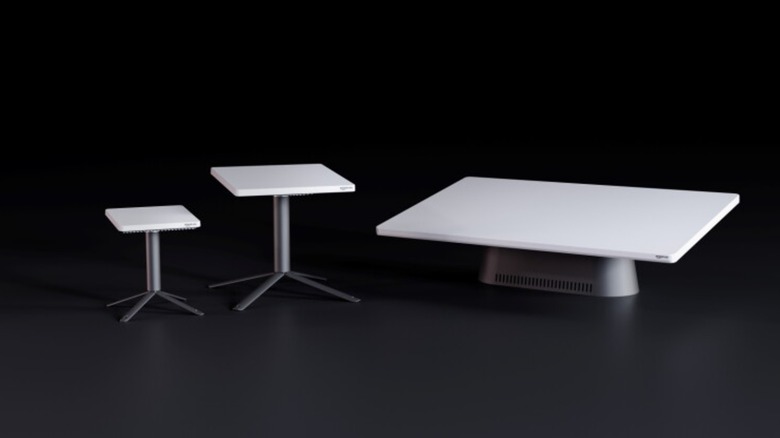 Three different sized Amazon Leo antennas all standing next to each other, each has a white rectangular block on a small platform