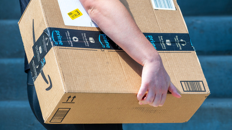 A person carrying an Amazon box under an arm