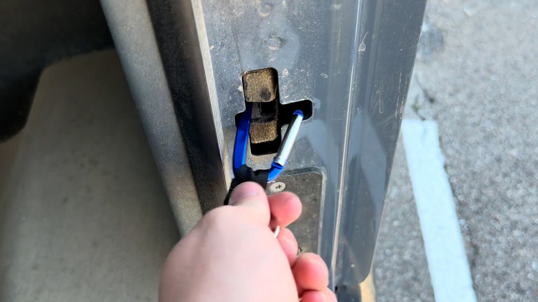 A carabiner clipped into the door latch of an Amazon-branded Rivian electric delivery van.