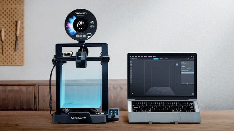 Creality Ender V3 SE on worktable next to laptop with slicing software