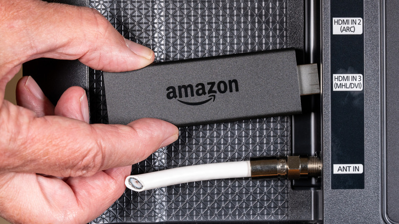 An Amazon Fire TV Stick being plugged into the back of a TV.