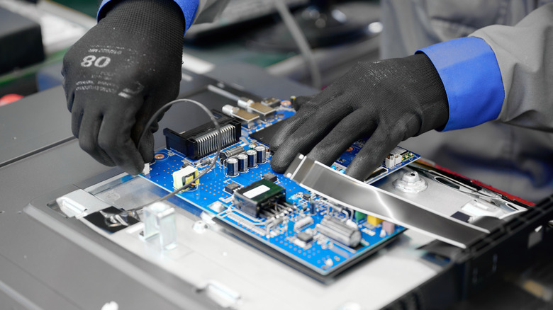 A TV manufacturer worker connecting board-level peripherals on a TV.