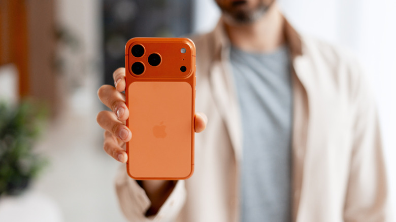 Man holding an iPhone 17 Pro Max with the rear of the phone facing the camera.