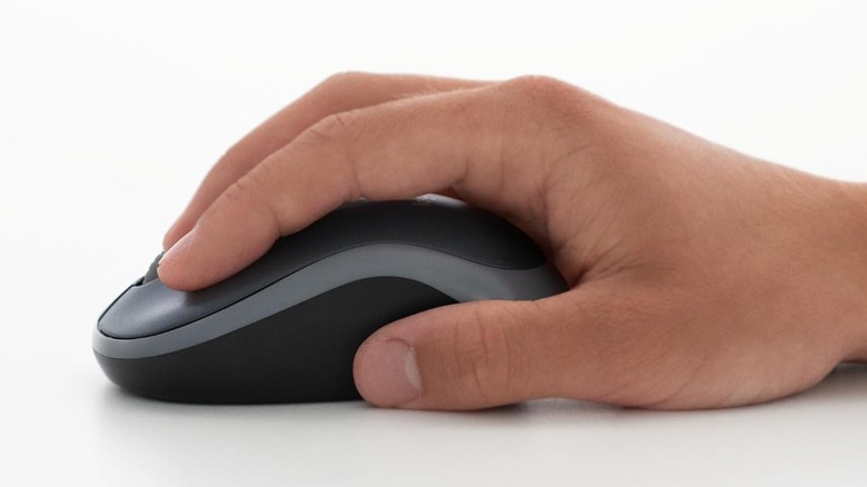 The right hand of an individual placed on top of a Logitech M185 office mouse with a grayish background