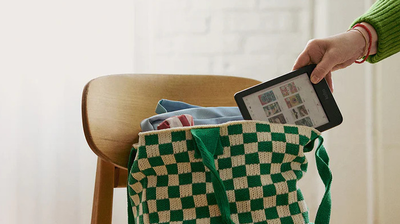A hand putting a Kobo Clara Colour into a purse that's sitting on a chair