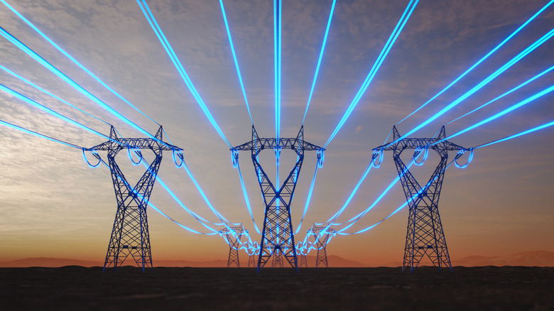 Concept image of power lines carrying electricity with an orange-blue sky in the background.