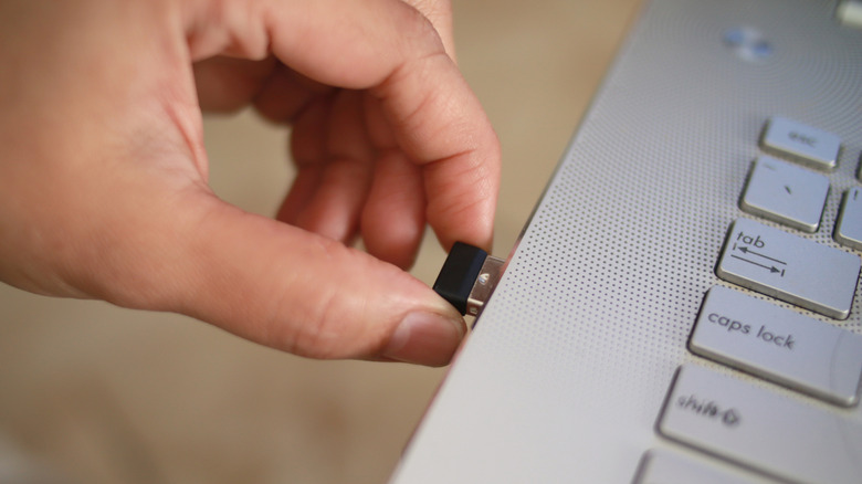 Person connecting a USB adapter to a laptop