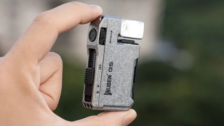 A closeup of an individual holding the Wuben G5 Rechargeable EDC Flashlight between their thumb and forefinger