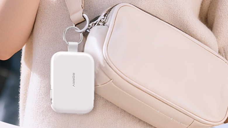 A white Rorry 5000mAh Portable Charger Power Bank attached to a soft pink person that's being worn by an individual in a soft pink sweater