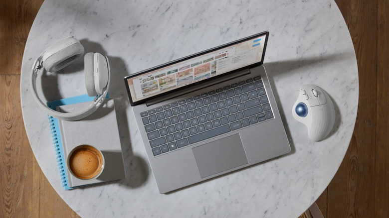 Logitech Ergo M575S Wireless Trackball Mouse on marble table with laptop, coffee, and headphones