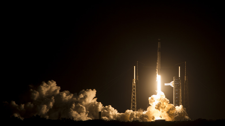 A SpaceX Falcon9 rocket jettisons off into space against a dark night sky.