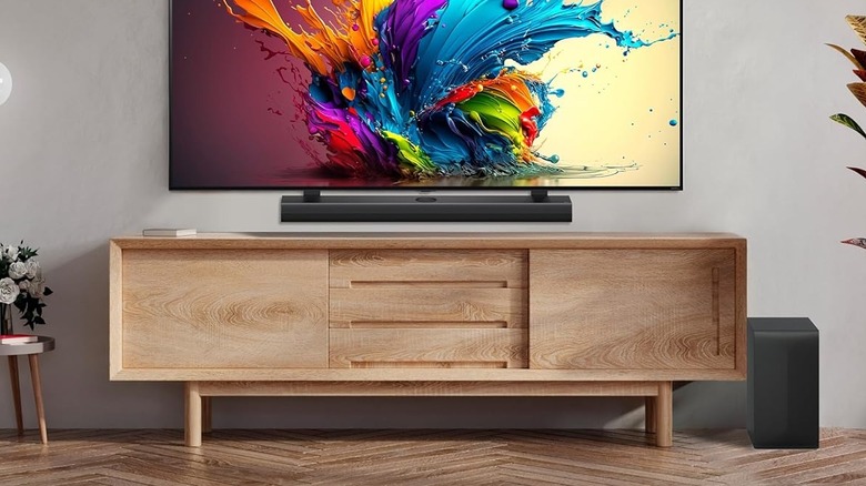 The LG S70TY Soundbar mounted below an LG TV. The wireless subwoofer is placed to the right of the TV stand.