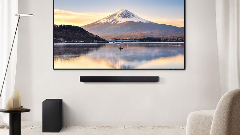 The Samsung HW-B550F Soundbar mounted below a TV, with its wireless subwoofer on the floor beneath it.